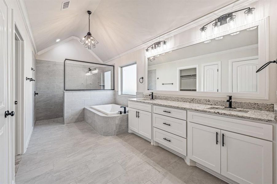 Bathroom with walk in shower, vaulted ceiling, double vanity, a chandelier, and tiled tub