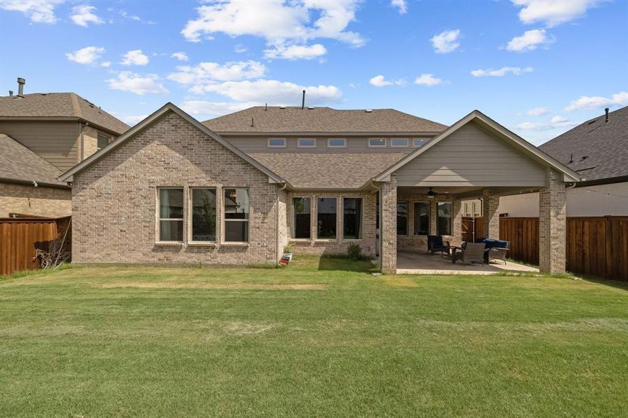 Back of property with a patio area, ceiling fan, a fenced backyard, and a lawn