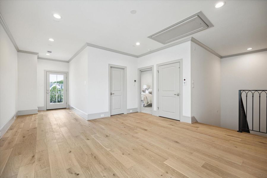 Third-floor game room, access to balcony through glass door on left, secondary bedroom through middle door on right.