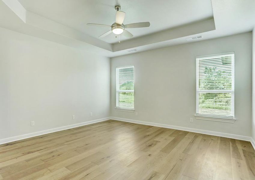 The master suite of the Mantle plan has gorgeous wood floors and a ceiling fan.