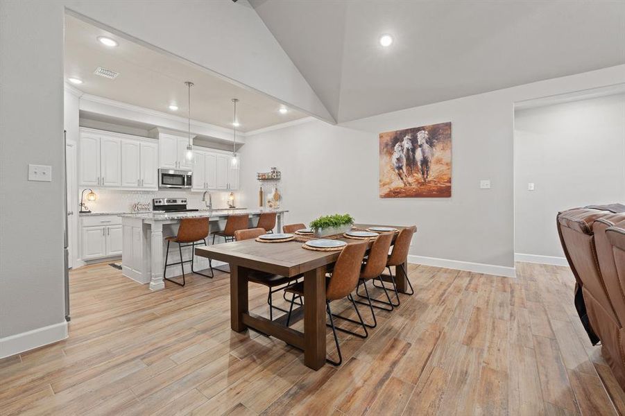 Dining space with vaulted ceiling, light wood-style floors, recessed lighting, and crown molding