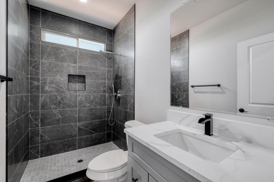 Full bath featuring vanity, toilet, and a tile shower