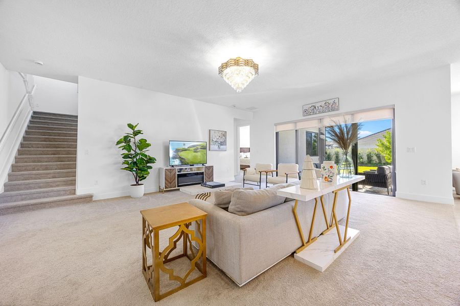 Living room with light carpet, a textured ceiling, and stairs