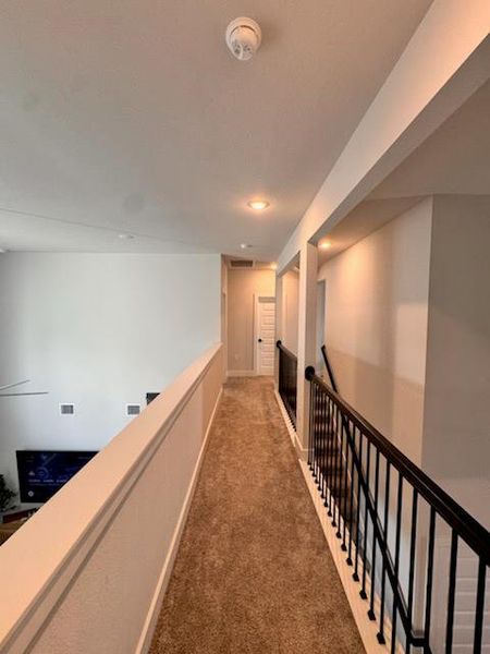 Corridor with carpet floors and an upstairs landing