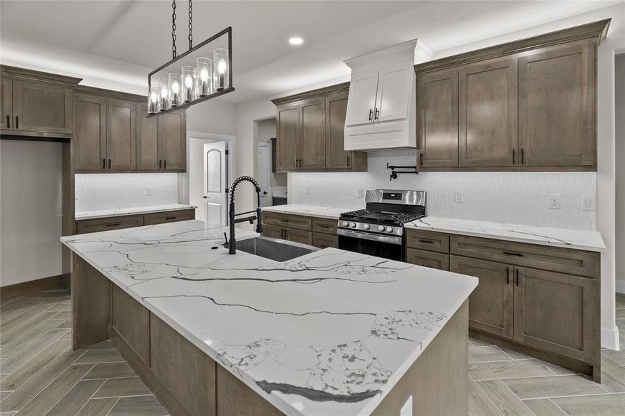 Kitchen featuring gas range, a sink, recessed lighting, tasteful backsplash, and a kitchen island with sink