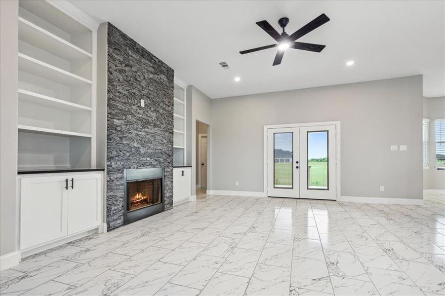 Unfurnished living room with visible vents, baseboards, marble finish floor, a ceiling fan, and built in features
