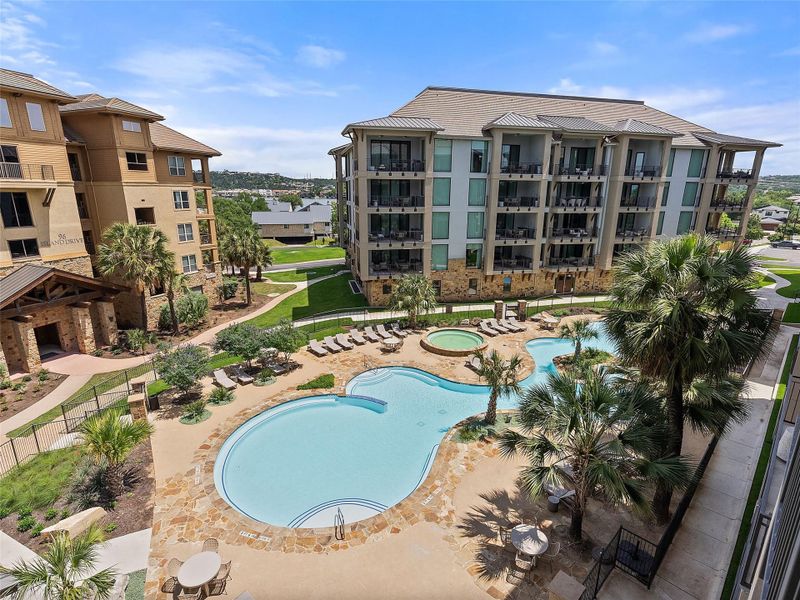 Expansive communal pool area featuring a free-form swimming pool, integrated spa, and surrounding stone patio Expansive communal pool area featuring a free-form swimming pool, integrated spa, and surrounding stone patio