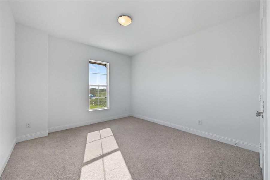 Spare room with light colored carpet and baseboards