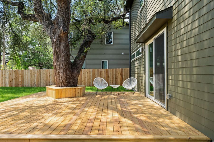 A spacious wooden deck provides an inviting outdoor area, complete with a built-in planter surrounding a mature tree. A spacious wooden deck provides an inviting outdoor area, complete with a built-in planter surrounding a mature tree.