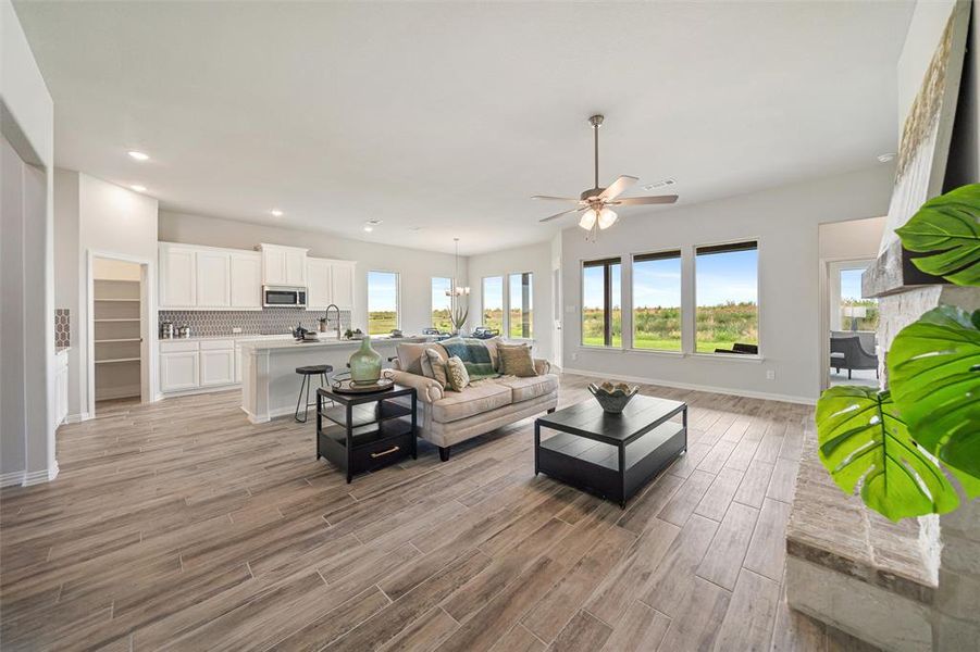 Living room with light wood-style flooring, a ceiling fan, recessed lighting, and a chandelier Living room with light wood-style flooring, a ceiling fan, recessed lighting, and a chandelier
