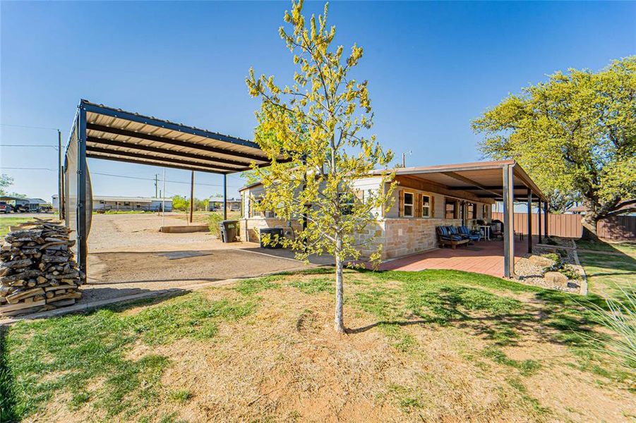 Back of house featuring stone siding, a detached carport, and a deck Back of house featuring stone siding, a detached carport, and a deck