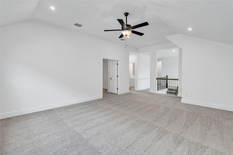 A spacious secondary living area features soft carpet and a convenient ceiling fan.
