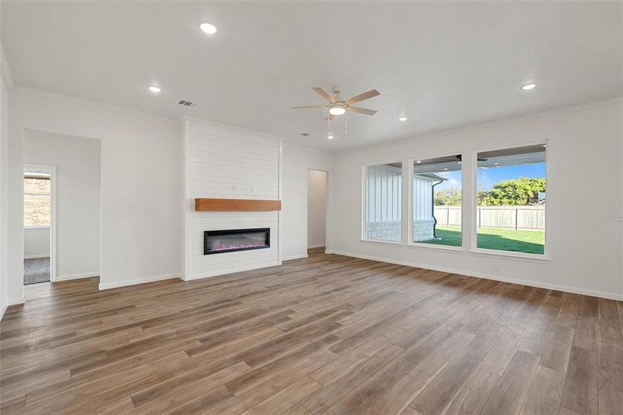 Unfurnished living room with ornamental molding, a fireplace, recessed lighting, a ceiling fan, and light wood-type flooring