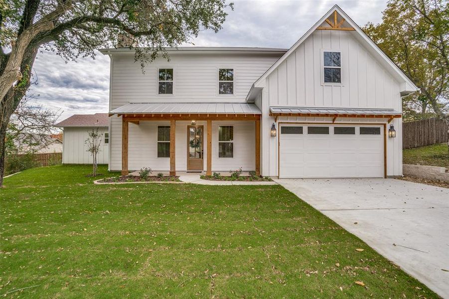 Modern farmhouse style home featuring covered porch and a front lawn