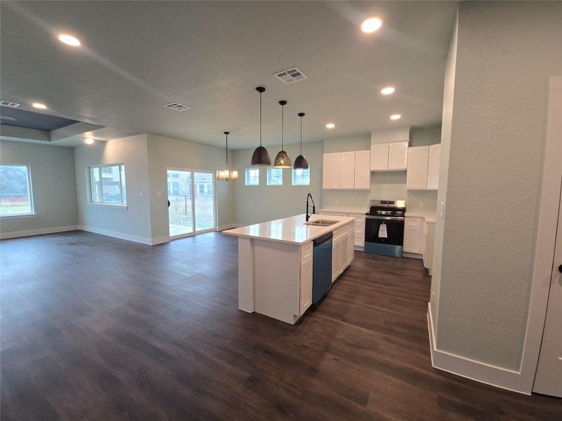 Kitchen featuring white cabinets, stainless steel range oven, open floor plan, recessed lighting, and pendant lighting