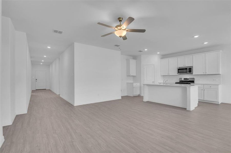 Kitchen featuring an island with sink, white cabinetry, light hardwood / wood-style flooring, stainless steel appliances, and ceiling fan