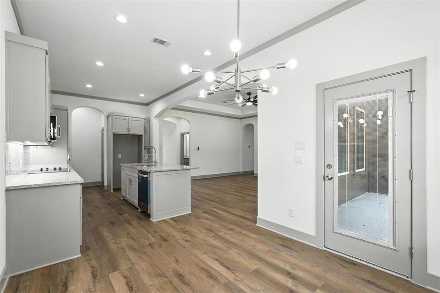 Kitchen with a chandelier, light stone countertops, a center island with sink, arched walkways, and recessed lighting Kitchen with a chandelier, light stone countertops, a center island with sink, arched walkways, and recessed lighting