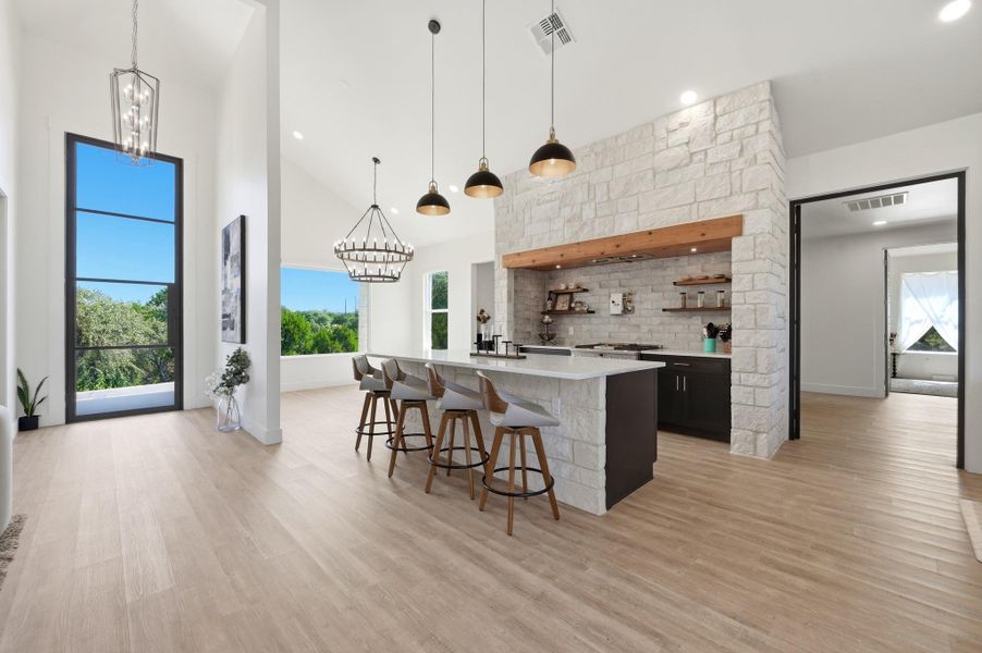Soaring ceilings and light wood floors define this expansive open-concept kitchen and living area.