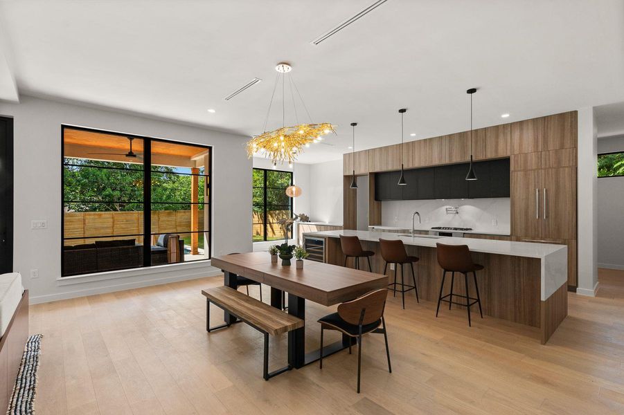 An open kitchen and dining area features warm wood flooring under a smooth minimalist ceiling.