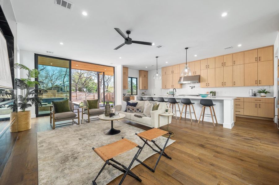 Living room with dark wood finished floors, visible vents, recessed lighting, and a wall of windows