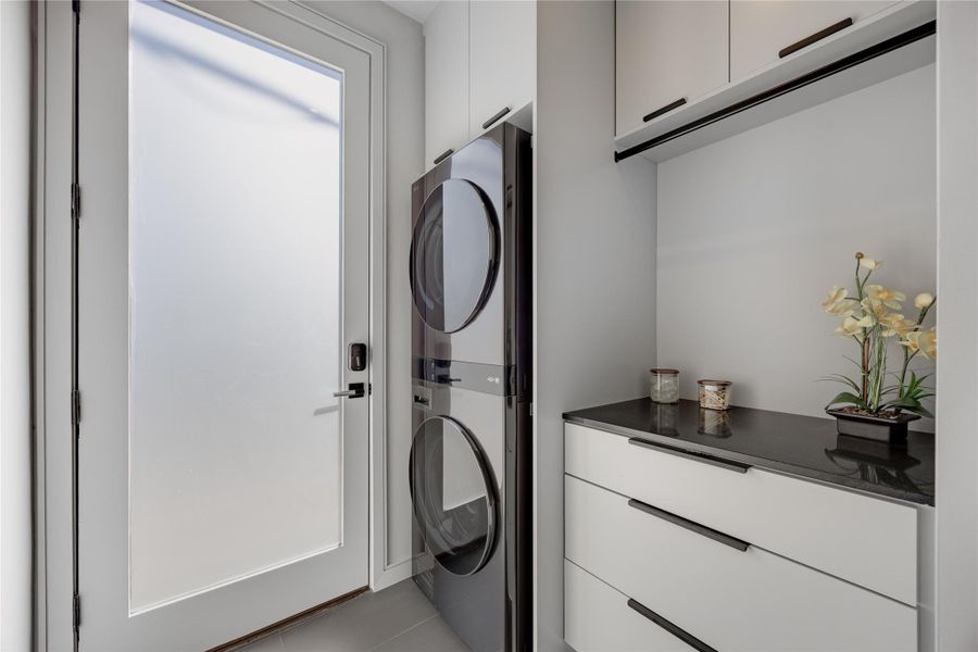 Laundry room with stacked washer / drying machine and cabinet space
