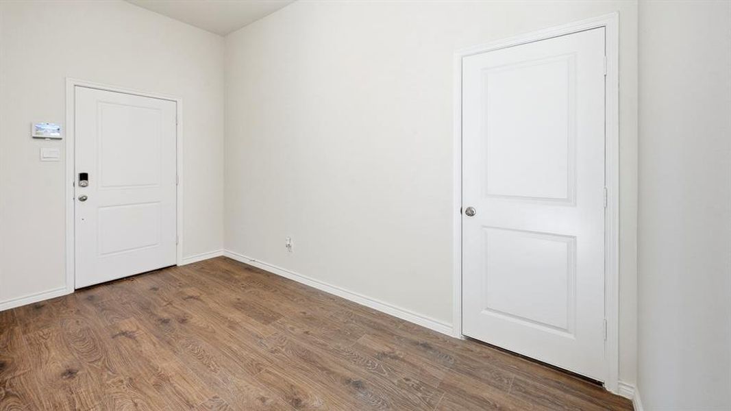 Empty room featuring baseboards and dark wood-type flooring