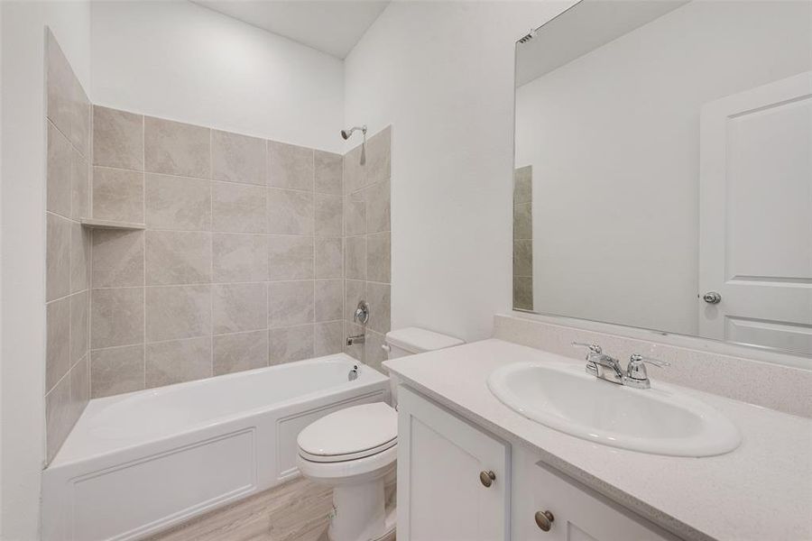 Full bathroom featuring tiled shower / bath combo, vanity, toilet, and wood-type flooring