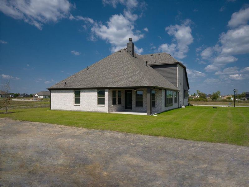 Back of house with brick siding, a shingled roof, a lawn, and a patio area Back of house with brick siding, a shingled roof, a lawn, and a patio area