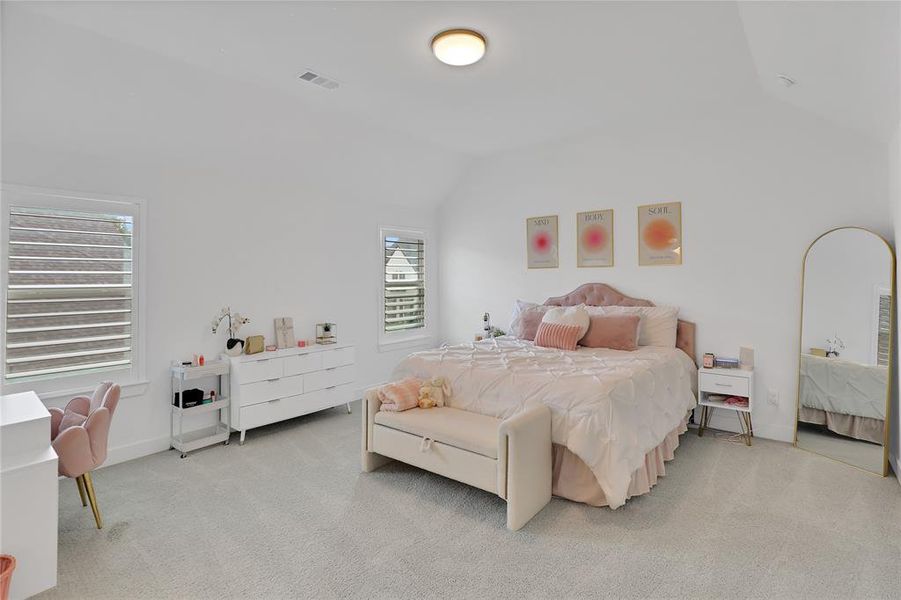 Spacious room with vaulted ceilings and light-toned carpet flooring