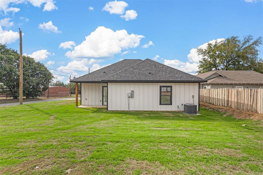 Back of property with a yard and central AC