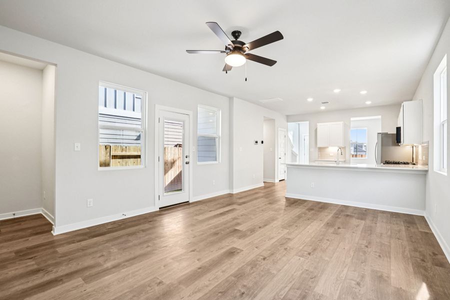A room with white walls and a wood floor with a ceiling fan.