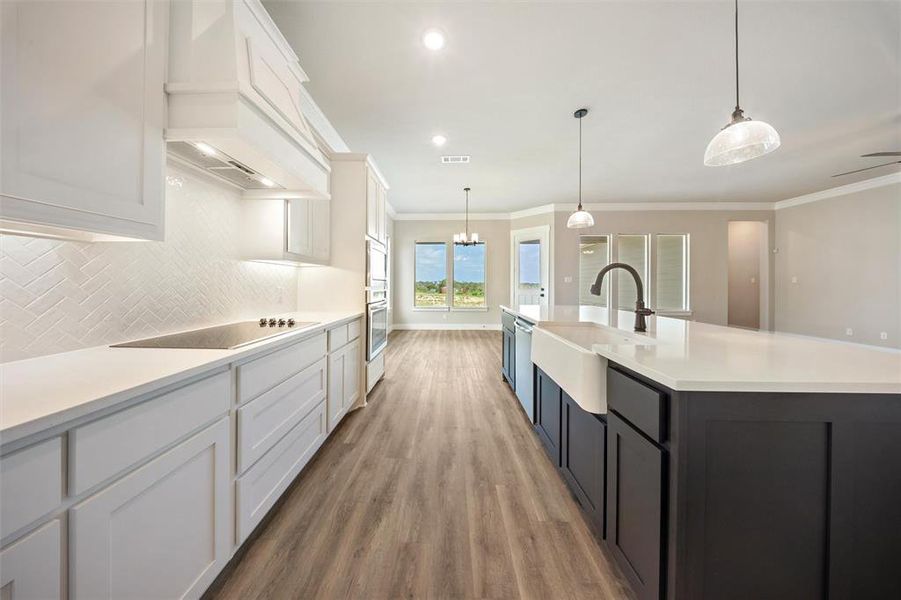 Kitchen with light wood finished floors, light countertops, white cabinetry, crown molding, and tasteful backsplash Kitchen with light wood finished floors, light countertops, white cabinetry, crown molding, and tasteful backsplash