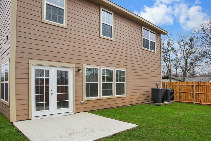 Back of property featuring a patio, a lawn, central air condition unit, and french doors