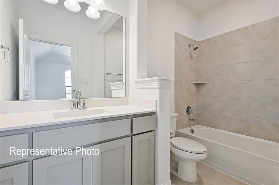 Full bathroom with tile patterned flooring, toilet, tiled shower / bath combo, and vanity