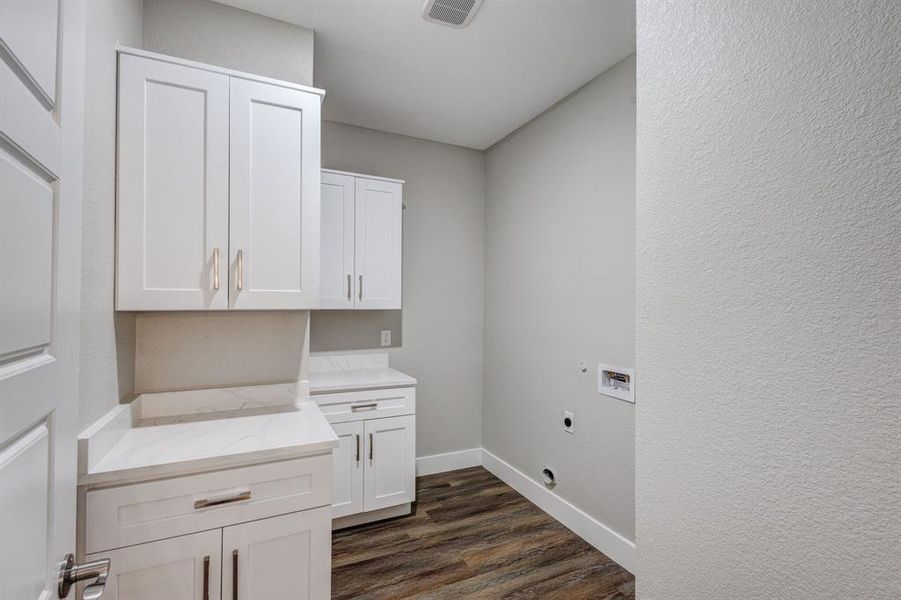 Clothes washing area featuring electric dryer hookup, washer hookup, dark hardwood / wood-style floors, and cabinets