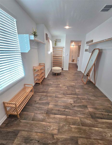 Spacious room featuring wood-finish flooring, white walls, and built-in shelving with hanging rods