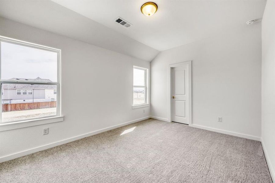 Unfurnished bedroom featuring vaulted ceiling and carpet flooring