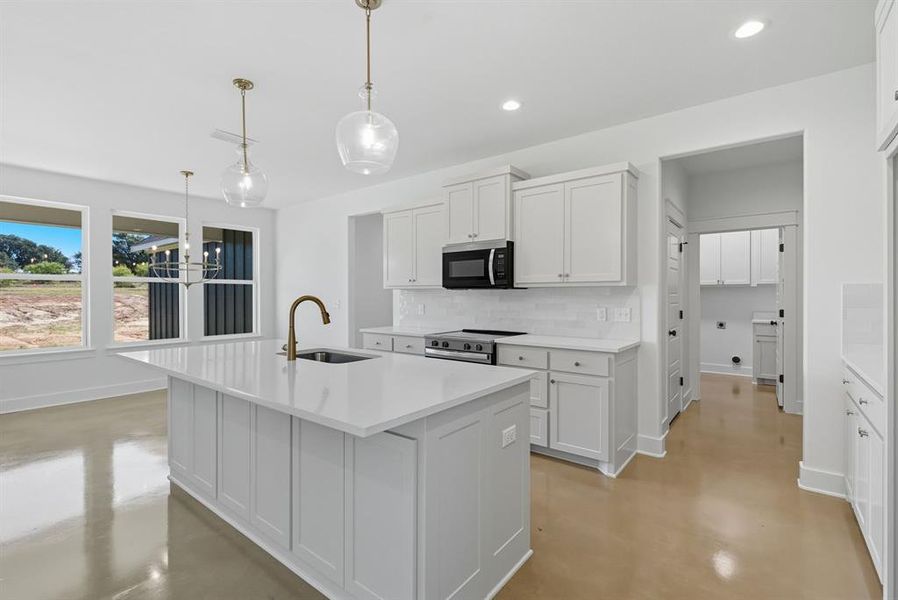 Kitchen with finished concrete floors, decorative backsplash, white cabinets, range with electric stovetop, and decorative light fixtures