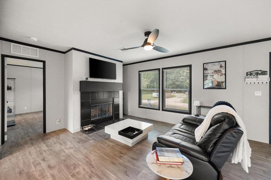 Living area featuring a contemporary ceiling fan, and a fireplace with a black tile surround and mantle Living area featuring a contemporary ceiling fan, and a fireplace with a black tile surround and mantle