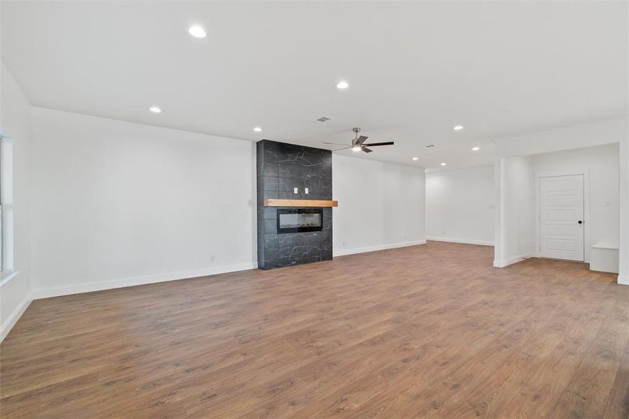 Unfurnished living room with hardwood / wood-style floors, ceiling fan, and a high end fireplace