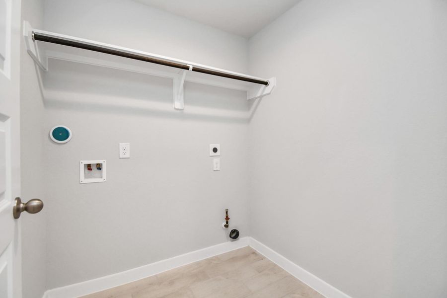 A spacious utility room with ample shelving for organization. It features connections for both gas and electric dryers, making it versatile and functional for all laundry needs. Sample photo of completed home with similar floor plan. Actual colors and selections may vary. A spacious utility room with ample shelving for organization. It features connections for both gas and electric dryers, making it versatile and functional for all laundry needs. Sample photo of completed home with similar floor plan. Actual colors and selections may vary.