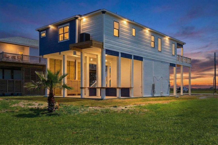 This elevated modern home features a sleek design with large windows and a spacious deck. It's set against a beautiful sunset backdrop, offering a serene and inviting atmosphere.