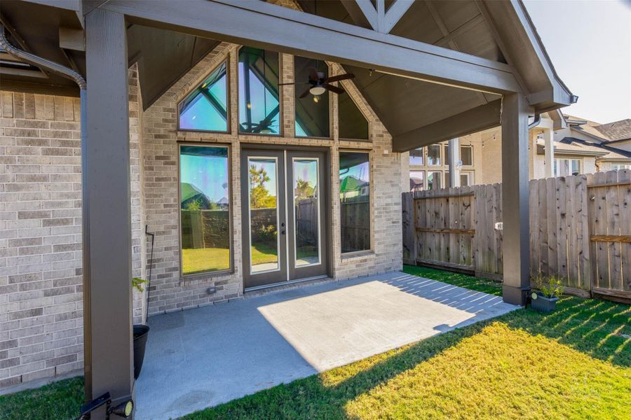 Enjoy a spacious vaulted covered patio complete with a ceiling fan, perfect for relaxing outdoors while staying shaded year-round. Architectural beams and the dramatic wall of windows create a beautiful extension of the home's modern design. Enjoy a spacious vaulted covered patio complete with a ceiling fan, perfect for relaxing outdoors while staying shaded year-round. Architectural beams and the dramatic wall of windows create a beautiful extension of the home's modern design.
