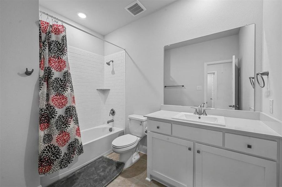 Bathroom featuring shower / bath combo with shower curtain, vanity, light tile patterned floors, and recessed lighting