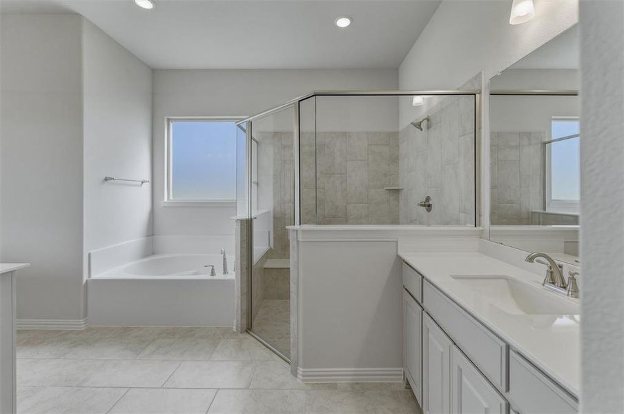 Bathroom featuring a tiled shower with glass enclosure, a white soaking tub with a window, a single vanity with an undermount sink, and light-toned floor tiling Bathroom featuring a tiled shower with glass enclosure, a white soaking tub with a window, a single vanity with an undermount sink, and light-toned floor tiling