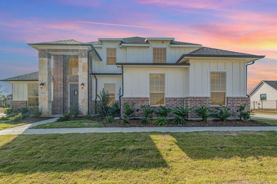 View of front of house featuring a front lawn, board and batten siding, and roof with shingles