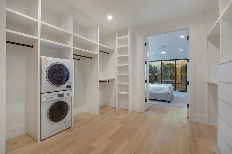 Washroom featuring light wood-type flooring, stacked washer / dryer, and a barn door