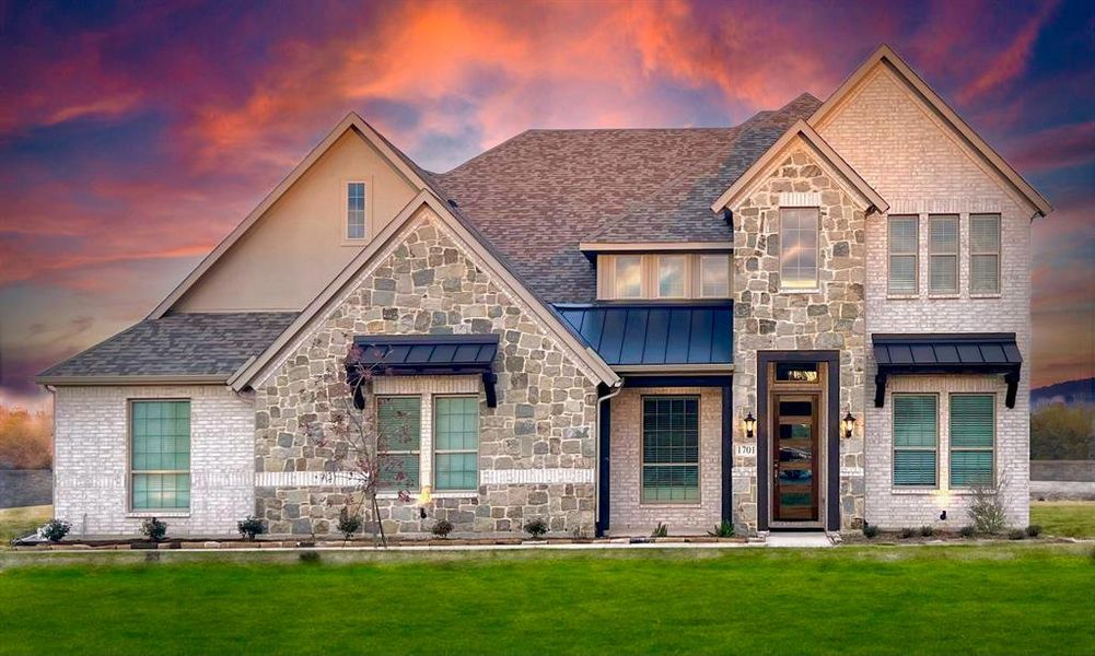 View of front of home with a shingled roof, metal roof, a standing seam roof, a front yard, and brick siding