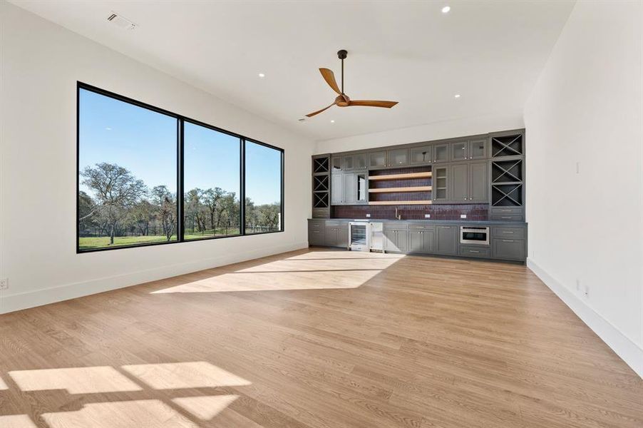 Unfurnished living room featuring bar with sink, wine cooler, light wood-style floors, ceiling fan, and recessed lighting