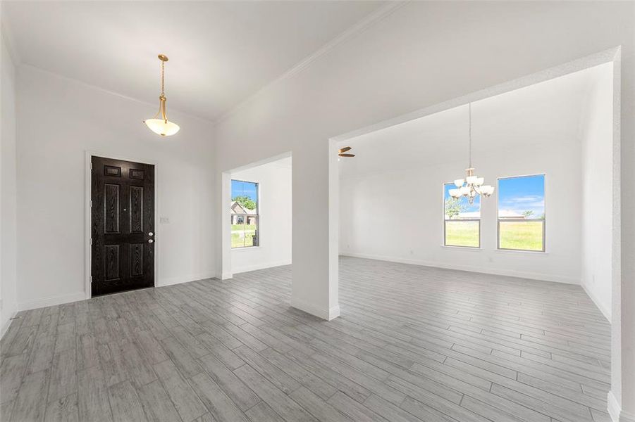 Foyer with healthy amount of natural light, a chandelier, crown molding, wood finished floors, and a towering ceiling